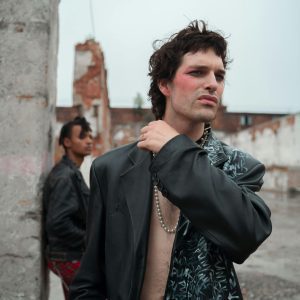 Moody Portrait Of Two Men In Stylish Outfits Against An Urban Backdrop.