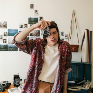 Young Man With Vintage Style Using An Analog Camera In A Retro Themed Room.
