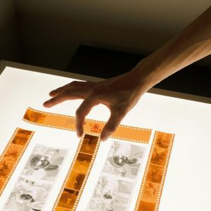 A Hand Delicately Chooses Film Negatives On A Well Lit Table, Showcasing Vintage Photography.
