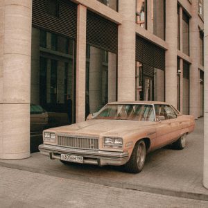 Vintage Car Beside Modern Architectural Columns. Urban Nostalgic Scene.