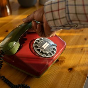 Close Up Of A Vintage Rotary Phone Being Held By A Senior Hand, Evoking Nostalgia.
