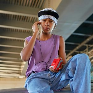 Teen Boy In Casual Attire Enjoying Music With A Walkman Under A Bridge.
