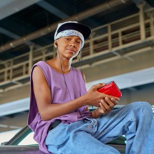 Teenage Boy Sitting Outdoors Listening To Music With A Walkman And Headphones.
