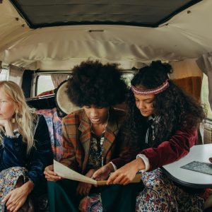 Group Of Friends In A Vintage Van Exploring Maps With A Hippie Vibe.