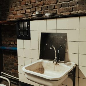Old Industrial Sink Against A Rustic Brick Wall, Highlighting Urban Decay.