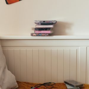Retro 90s Bedroom Featuring A Stack Of Cassette Tapes, A Cassette Player, And Nostalgic Posters.