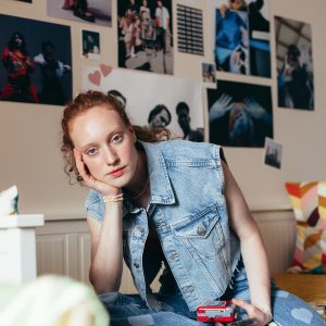 Caucasian Woman In Denim Fashion Holding A Cassette Player, Seated Casually.