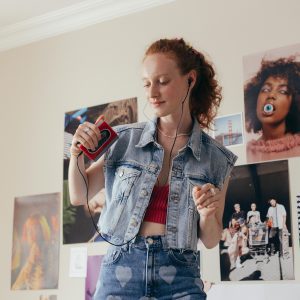 Woman Enjoying Music With A Retro Cassette Player And Earphones, Embracing 90s Style.