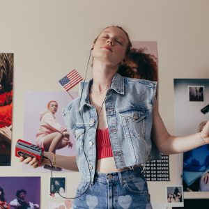 A Young Woman In Denim Enjoying Music In Her Bedroom, Embracing A Retro Style With A Walkman And Vibrant Posters.