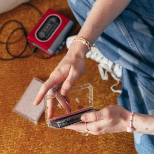 Close Up Of Hands Navigating Cassettes On A Vintage Carpet, Evoking 90s Nostalgia.