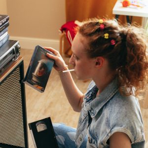 Woman Enjoying Nostalgic VHS Tapes In A Cozy Indoor Setting, Reliving The 90s Charm.