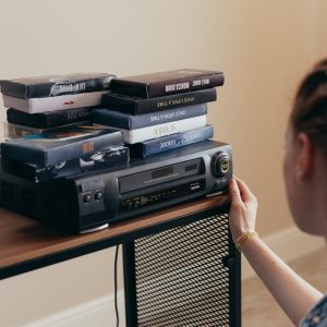Young Woman Engaging With Retro VHS Tapes And A Classic VCR Setup.