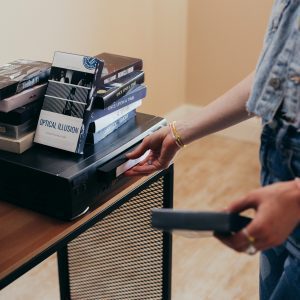 A Person Setting Up A VCR With VHS Tapes In A Cozy Indoor Setting.