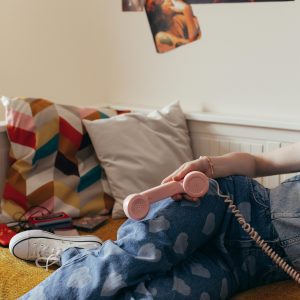 A Nostalgic 90s Style Bedroom With Denim Jeans, Cassette Tapes, And A Vintage Telephone.