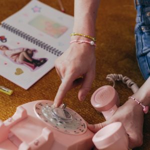 Retro Themed Image Featuring A Pink Rotary Phone Being Dialed, Evoking 90s Nostalgia.