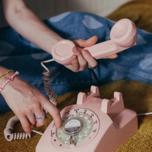 Close Up Of A Vintage Pink Rotary Phone Being Dialed By A Woman.