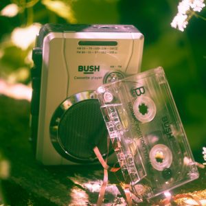 Vintage Cassette Player And Tape In An Outdoor Green Setting With Sunlight.