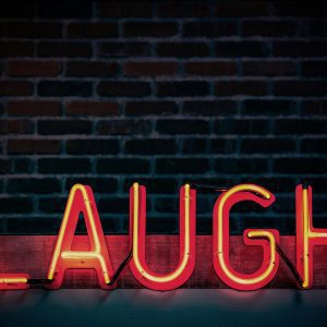 Bright Neon Sign Displaying 'LAUGH' Against A Dark Brick Wall, Creating A Vibrant Mood.