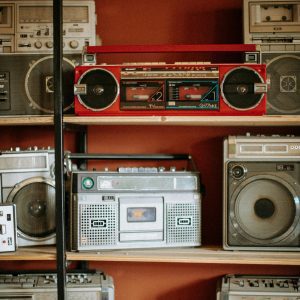 A Diverse Collection Of Vintage Radios And Boomboxes Displayed On Wooden Shelves.