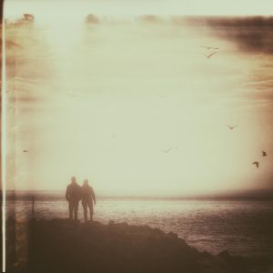 A Romantic Vintage Photo Of A Couple Walking At Sunset By The Ocean, Creating A Serene And Nostalgic Mood.