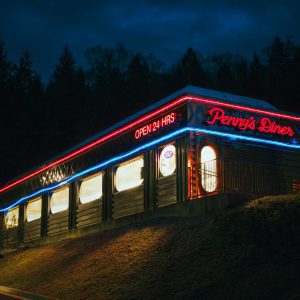 Diner Exterior With Vibrant Neon Lights At Night, Offering A Retro Ambiance.