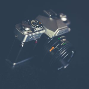A Close Up Of A Vintage Film Camera With A Classic Lens, Showcasing A Retro Design On A Dark Background.