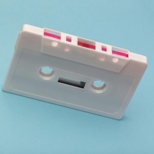 Vintage White Cassette Tape Against A Vibrant Blue Backdrop, Capturing Classic Audio Technology Nostalgia.