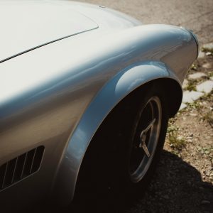 Close Up Of A Vintage Car Showing The Classic Fender Design With Sunlight Highlighting Its Contours.