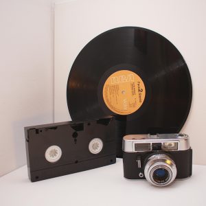 Retro Technology Enthusiasts Will Love This Classic Mix Of Vinyl Record, Analog Camera, And VHS Tape.