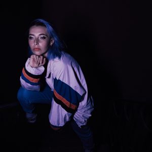 Artistic Portrait Of A Young Woman With Blue Hair And Casual Attire, In A Moody Setting
