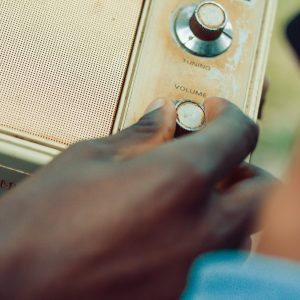 Hand Adjusting Volume On A Vintage Radio In An Outdoor Setting.