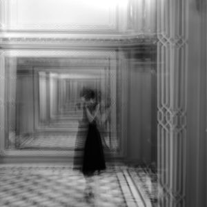 Artistic Black And White Photo Of A Corridor With A Blurred Silhouette, Creating A Surreal Effect.