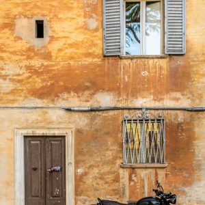 A Classic Motorcycle Parked By A Weathered Wall In Urbino, Italy, Showcasing Timeless Architecture.