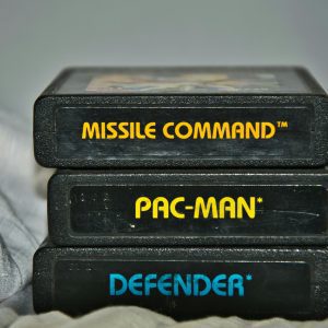 Close Up Of Vintage Atari Game Cartridges For Missile Command, Pac Man, And Defender.
