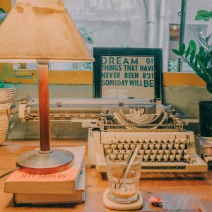 A Serene Indoor Setting With A Vintage Typewriter, Lamp, And Plants, Perfect For Creativity.