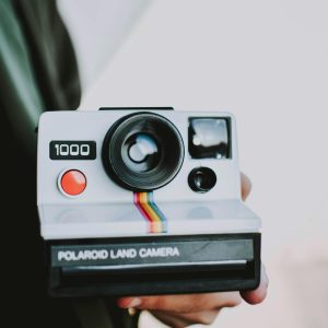 Close Up Of A Retro Polaroid Camera Being Held, Showcasing Vintage Photography Style.