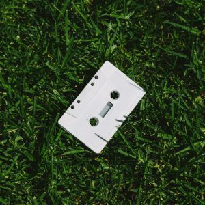Vintage White Cassette Tape On Lush Green Grass, Sunny Day Outdoor Shot.