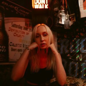A Contemplative Woman In Urban Decor With Neon Lights And Posters.