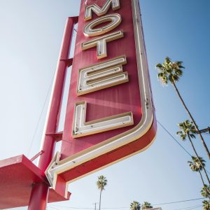 Vintage Motel Sign In Los Angeles With Palm Trees Under A Clear Blue Sky.
