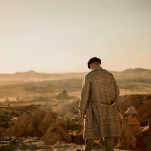 A Man In Fashionable Attire Overlooking The Scenic Landscape Of Ortahisar, Cappadocia At Sunset.