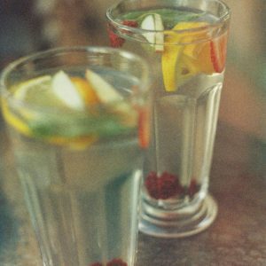 Two Glasses Of Citrus And Berry Infused Water Sit Elegantly On A Bar Counter.