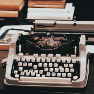 Close Up Of An Antique Typewriter On A Desk Surrounded By Books, Evoking A Classic Retro Style.