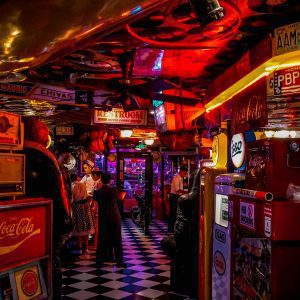 Vintage Arcade Bar With Retro Signs, People, And Neon Lights.