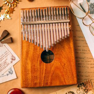 Close Up Of A Wooden Kalimba Amidst Vintage Papers And Eyeglasses.