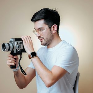 Man Holding A Vintage Camera In A Studio Setting, Creating A Retro Vibe.