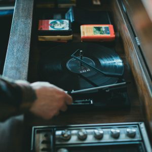 Close Up Of A Vintage Turntable Playing A Vinyl Record With Visible Hand Adjusting. Classic Music Setup Indoors.