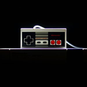 A Close Up Of A Classic NES Controller With Dramatic Lighting On A Black Background, Evoking Nostalgia.