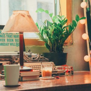 A Nostalgic Vintage Workspace Featuring A Typewriter, Coffee, Books, And Plants, Creating A Warm And Inviting Ambiance.