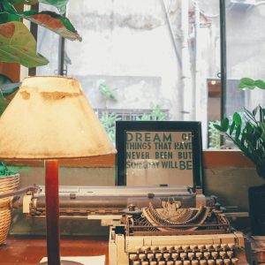 A Cozy Vintage Setting With A Typewriter, Lamp, And Open Window, Evoking Nostalgia And Creativity.