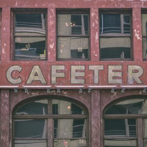Close Up Of A Weathered Cafeteria Facade With Reflective Windows In An Urban Setting.